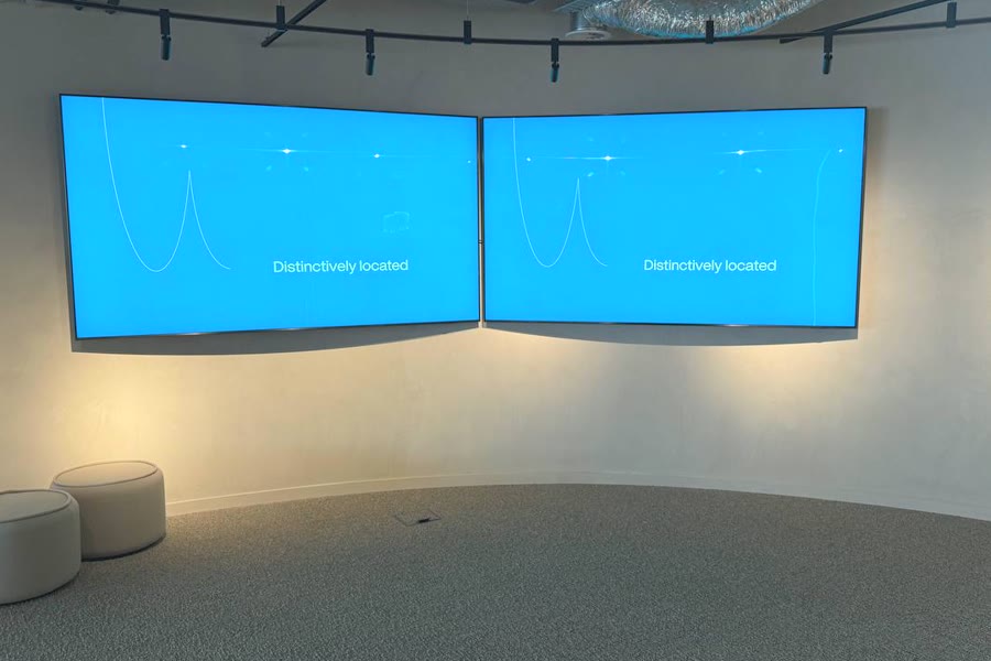 Two screens on a curved wall at Covent Garden, Brussels, showing the same frame of one video