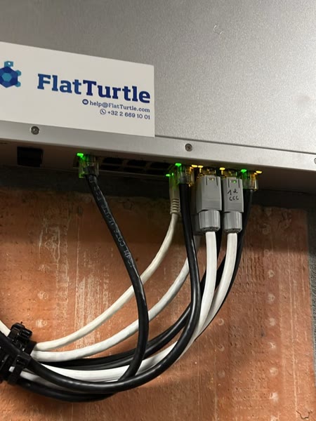 A FlatTurtle-labelled network switch with patched cables in a technical room